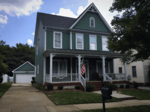 Front view of a house in green color with american flag