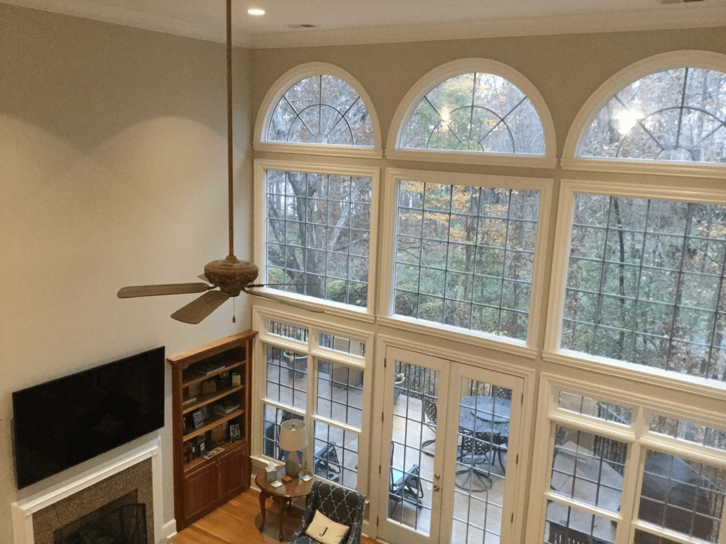 Ceiling fan and large windows overlooking a patio.
