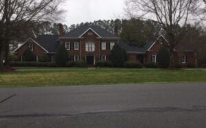 Long shot of a house with grass and plant bushes front