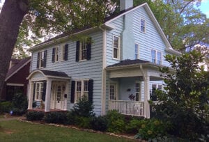 Side view of a house in pale blue color surrounded by trees