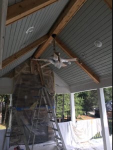 Grey ceiling with exposed beams and a fan.