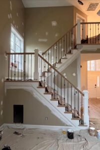 Unfinished staircase with black railing.