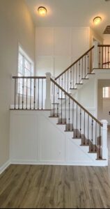 White staircase with black railing and wood steps.