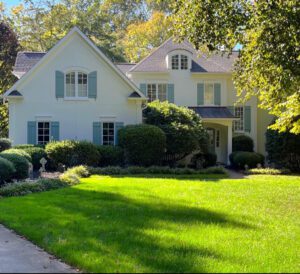 White house with blue shutters and green lawn.