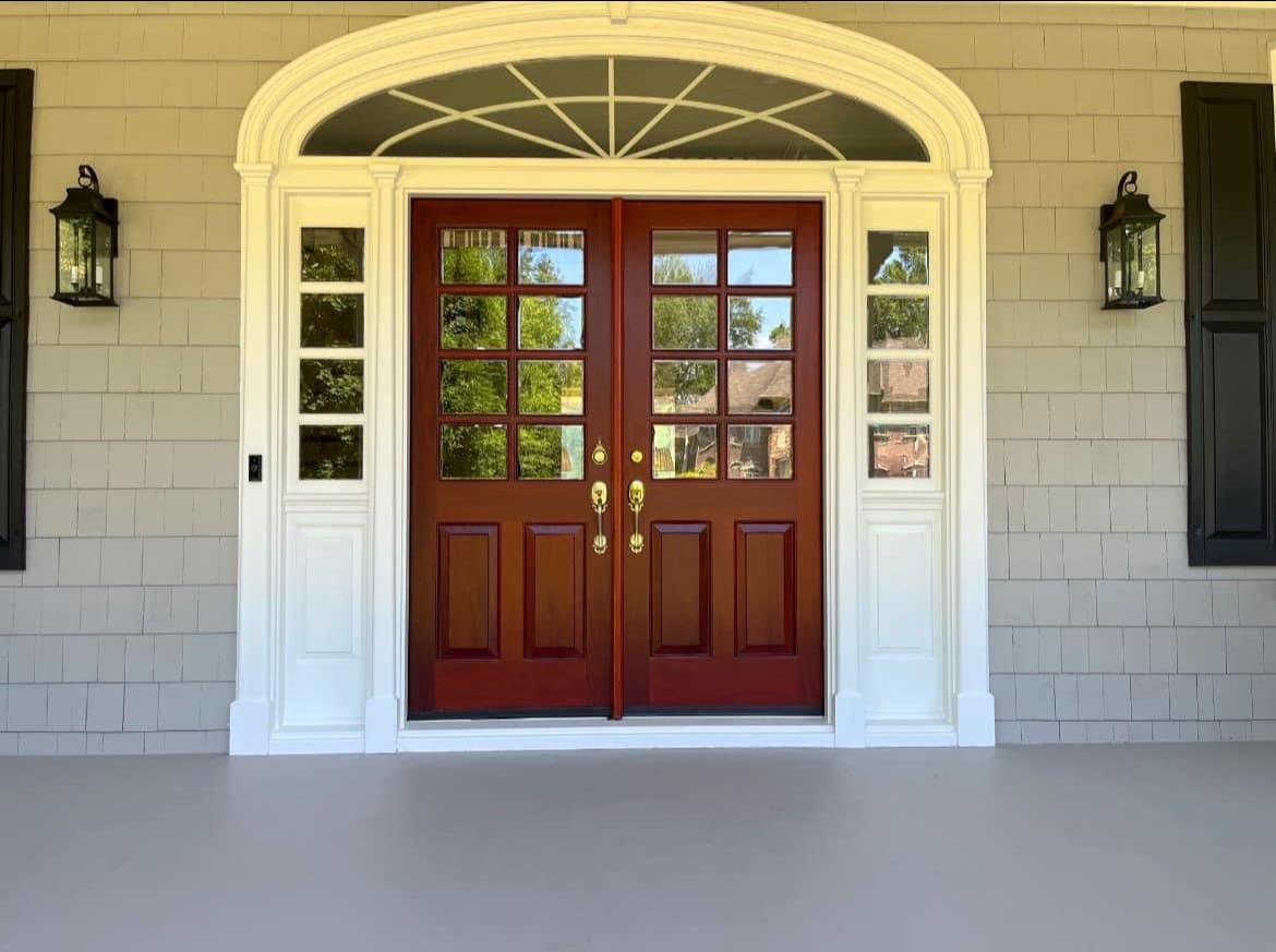 Red-brown double doors flanked by white sidelights