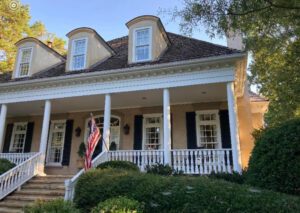 Beige house with porch and American flag.