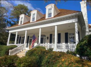 White house with porch and American flag.