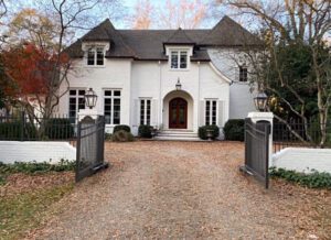 White house with gated driveway and fall leaves.