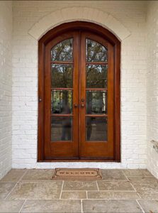 White brick porch with wooden double doors.