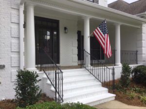 White brick house with porch and American flag.