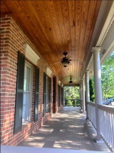 Brick porch with wood ceiling and fan.