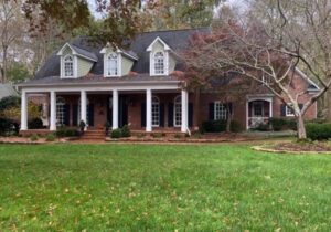 Brick house with white columns and porch.