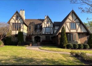 Large, white, Tudor-style house with a lawn.