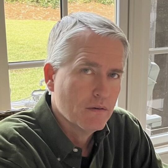 Man with gray hair wearing a green shirt.